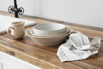 Clean towel and dishes on wooden counter in kitchen, closeup