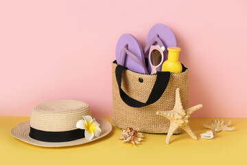 Wicker bag with bottle of sunscreen cream, seashells and beach accessories on color background