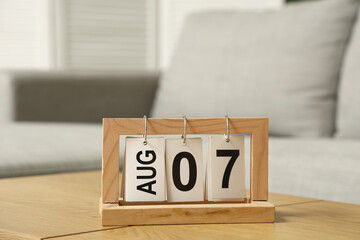 Flip calendar with date 7 AUGUST on table in room, closeup