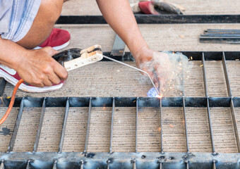 A worker is welding a drainage grate cover.