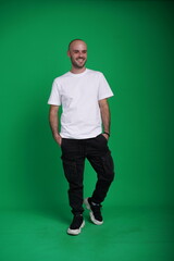 Young man with a variety of emotions, wearing a white t-shirt standing against a green background. Studio shot with copy space.