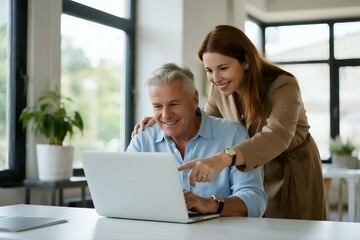 Couple Collaborating on Laptop: A smiling couple, an older man and a younger woman, looking at a laptop together, with the woman pointing at the screen.