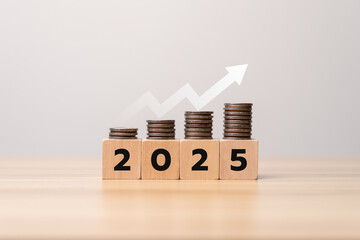 Saving money and financial planning in 2025 with increasing stacked coins on wooden blocks and rising arrow graph symbolizing investment growth, business success, wealth management and economic goals