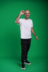 Fototapeta premium Young man with a variety of emotions, wearing a white t-shirt standing against a green background. Studio shot with copy space.
