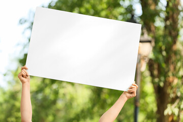 Female hands holding blank poster in park