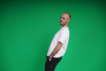 Fototapeta premium Young man with a variety of emotions, wearing a white t-shirt standing against a green background. Studio shot with copy space.