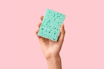 Hand holding sponge for cleaning on pink background