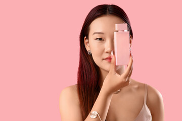 Beautiful Asian woman with perfume on pink background, closeup