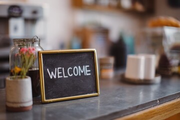 A Warm Welcome Sign on a Coffee Shop Counter Invites Customers to Enjoy the Cozy Atmosphere and Delicious Beverages Offered