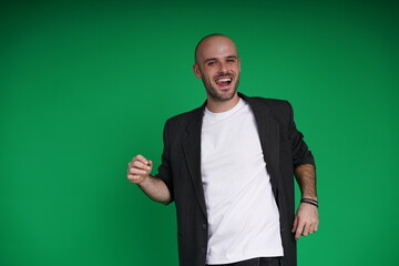 Young man with a variety of emotions, wearing a white t-shirt standing against a green background. Studio shot with copy space.