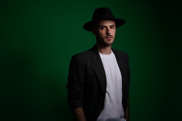 Young man with a variety of emotions, wearing a white t-shirt standing against a green background. Studio shot with copy space.