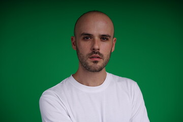Young man with a variety of emotions, wearing a white t-shirt standing against a green background. Studio shot with copy space.