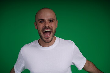 Fototapeta premium young man wearing a white t-shirt standing against a green background. Studio shot with copy space.