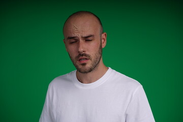 young man wearing a white t-shirt standing against a green background. Studio shot with copy space.