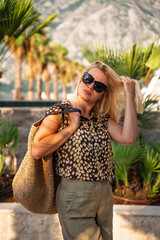 Beautiful blonde with sunglasses on vacation, waist shot palms in the back 