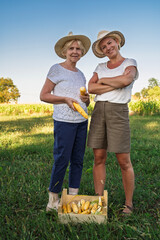 Mother and daughter , family business posing on the agricultural field with hand picked corn in the...