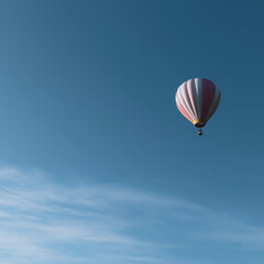 Fototapeta premium Soaring High: A solitary hot air balloon floats majestically against a backdrop of an endless, brilliant blue sky, offering a sense of adventure and freedom.