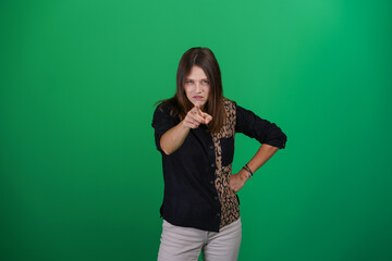A young woman poses in a studio with a green background, showing natural emotions, full of expressions and dynamic movements. Unedited image