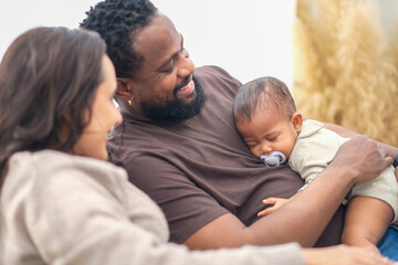 Fototapeta premium Portrait of enjoy happy love family african american father playing with little african american baby girl on sofa in living room. play, having fun, daughter, parenthood, loving care.