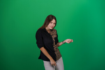 A young woman poses in a studio with a green background, showing natural emotions, full of expressions and dynamic movements. Unedited image