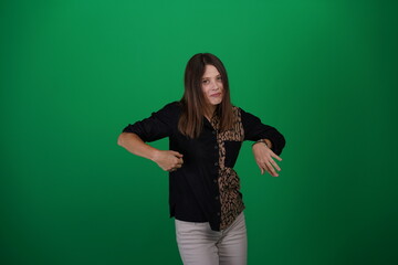 A young woman poses in a studio with a green background, showing natural emotions, full of expressions and dynamic movements. Unedited image
