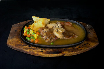 Beef steak with potatoes and vegetables, on wooden table