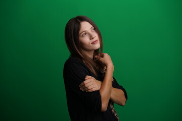 A young woman poses in a studio with a green background, showing natural emotions, full of expressions and dynamic movements. Unedited image
