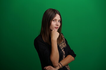 A young woman poses in a studio with a green background, showing natural emotions, full of expressions and dynamic movements. Unedited image
