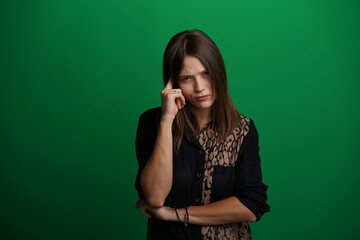A young woman poses in a studio with a green background, showing natural emotions, full of expressions and dynamic movements. Unedited image
