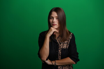 A young woman poses in a studio with a green background, showing natural emotions, full of expressions and dynamic movements. Unedited image