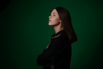 A young woman poses in a studio with a green background, showing natural emotions, full of expressions and dynamic movements. Unedited image