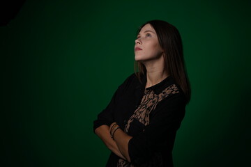 A young woman poses in a studio with a green background, showing natural emotions, full of expressions and dynamic movements. Unedited image