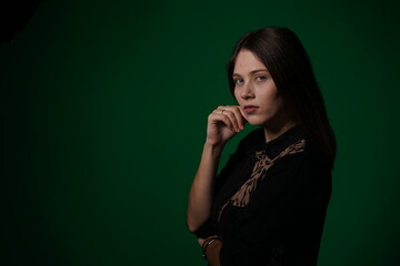A young woman poses in a studio with a green background, showing natural emotions, full of expressions and dynamic movements. Unedited image