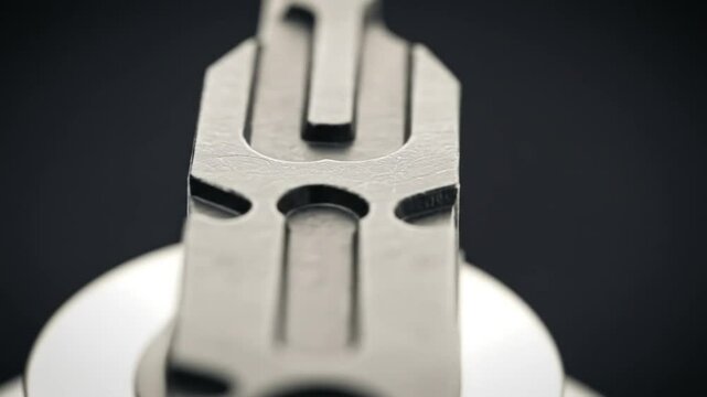 Extreme close up of a metal multi tool with cutouts and sharp edges on a dark background