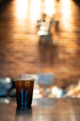 Close up of a refreshing iced black coffee or Americano place on wood table at orange lighting tone...