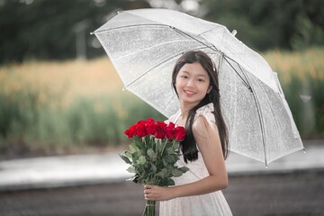 Young Girl Holding Red Roses Under Clear Umbrella in Rainy Weather