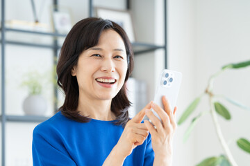 リビングでスマホを使うミドルの女性