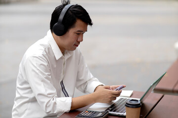 man wearing headphones while typing data on a laptop for communication or entertainment