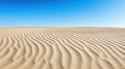 Naklejka premium Smooth sand dunes create serene landscape under clear blue sky, evoking tranquility and beauty