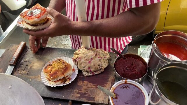 An Indian man making Mumbai famous Vada Pav in the streets of India.