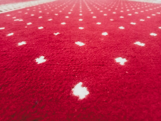 The texture of the red carpet with a white dot motif neatly arranged in a straight line gives an elegant impression as a background for industrial product catalog design.