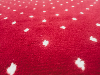 The texture of the red carpet with a white dot motif neatly arranged in a straight line gives an elegant impression as a background for industrial product catalog design.