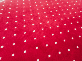 The texture of the red carpet with a white dot motif neatly arranged in a straight line gives an elegant impression as a background for industrial product catalog design.