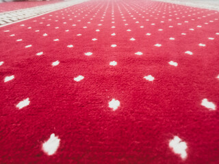 The texture of the red carpet with a white dot motif neatly arranged in a straight line gives an elegant impression as a background for industrial product catalog design.