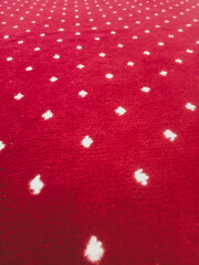 The texture of the red carpet with a white dot motif neatly arranged in a straight line gives an elegant impression as a background for industrial product catalog design.