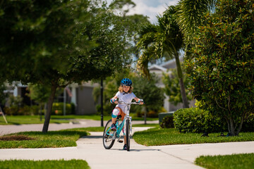 Cute kid riding a bike in summer park. Children learning to drive a bicycle on a driveway outside....