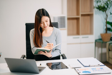 Confident Asian woman with a smile standing holding notepad and tablet