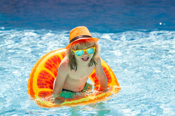 Child in swimming pool with inflatable toy ring. Children summer vacation. Swim for child on float....