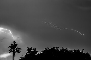 The light of lightning streaks across the sky as rain falls.