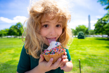 Summer kids face. Child eating ice cream. Summer sweets. Kid licking ice cream cone in summer park....